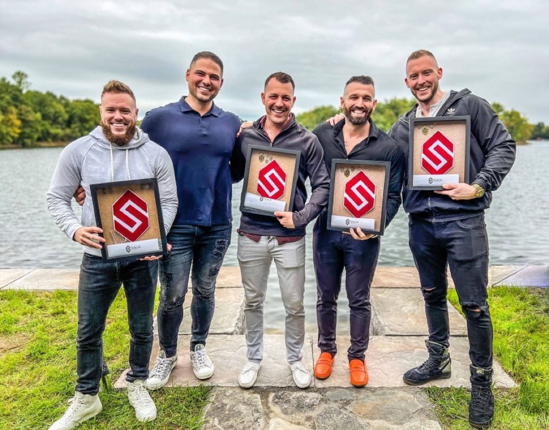 Five Serur Organization leaders holding their award plaques at a lakeside retreat